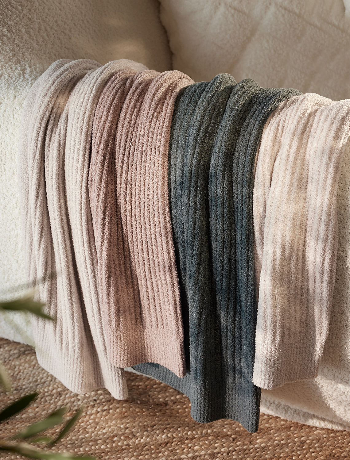 Set of folded knit blankets in various colors on a textured surface.