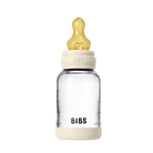 Clear baby bottle with beige cap and heart-shaped nipple on a white background