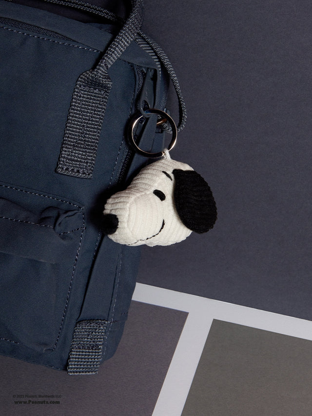 Keychain with a dog design attached to a navy blue bag on a gray surface.