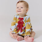 Baby wearing a colorful outfit with a red letter 'A' on a light background
