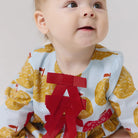 Baby wearing a bib with yellow fruit pattern and a red bow