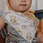 Baby wearing a bib with cartoon characters and a checkered outfit.