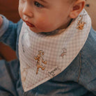 Child wearing a bib with cartoon characters and a denim jacket.