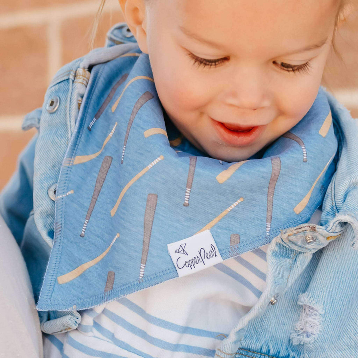 Child wearing a blue denim jacket with a patterned bib, featuring the brand 'Copper Pearl'.
