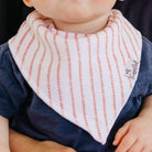 Baby wearing a striped bib with a brand label