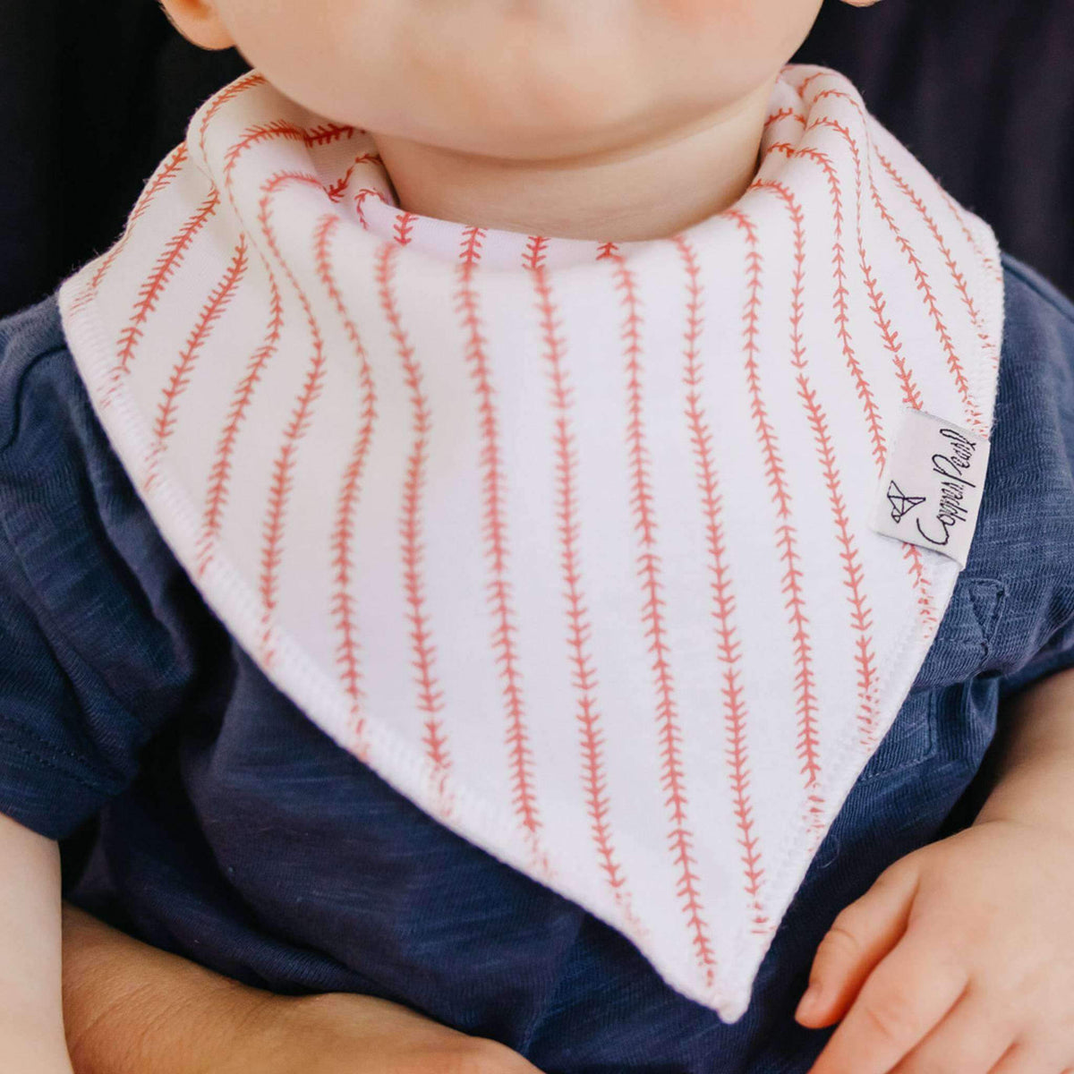 Baby wearing a striped bib with a brand label