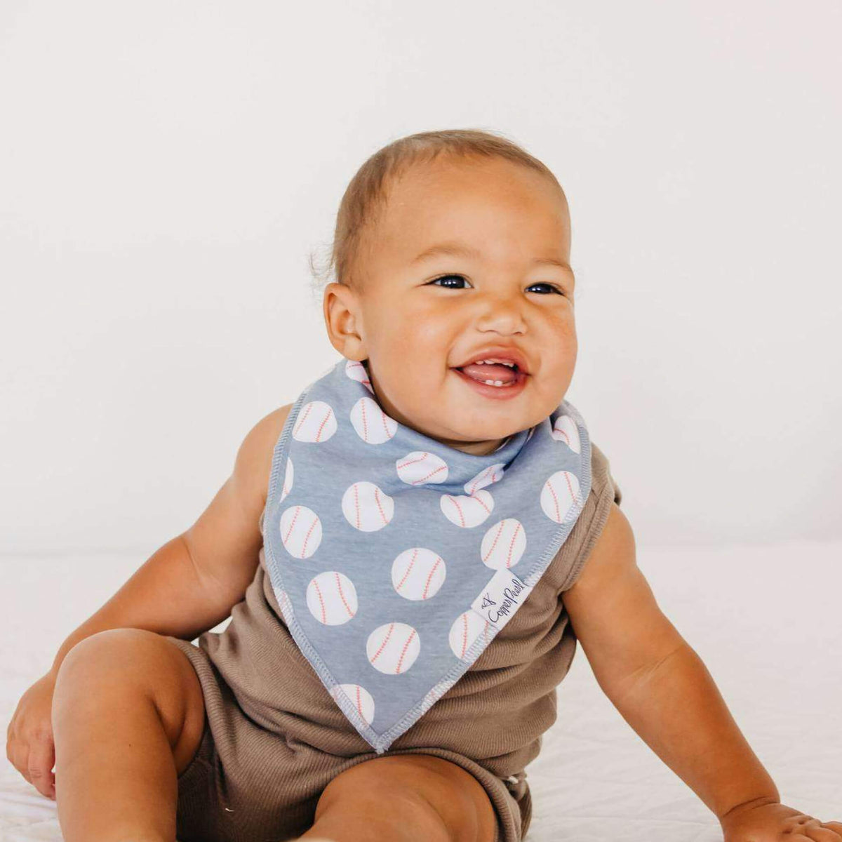 Baby wearing a bib with baseball pattern on a plain background