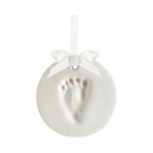 White ceramic ornament with baby footprint and ribbon on a white background