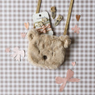 Fluffy bear-shaped bag with decorative elements on a checkered background
