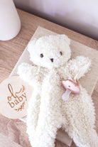 A cream-colored, curly teddy bear plush toy with small black embroidered eyes and nose.