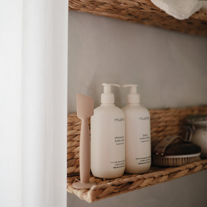 Two white bottles with pump dispensers on a wicker shelf.