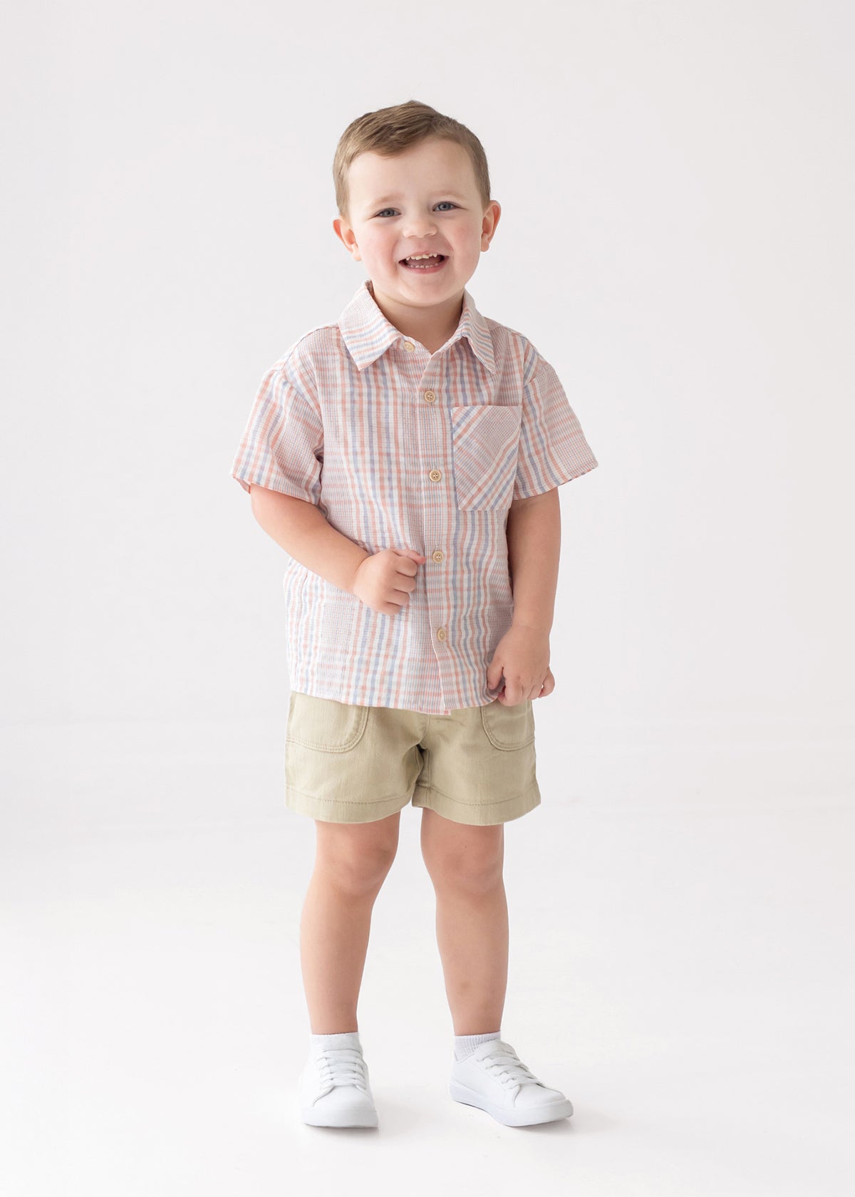 Child wearing a checkered shirt and shorts on a white background