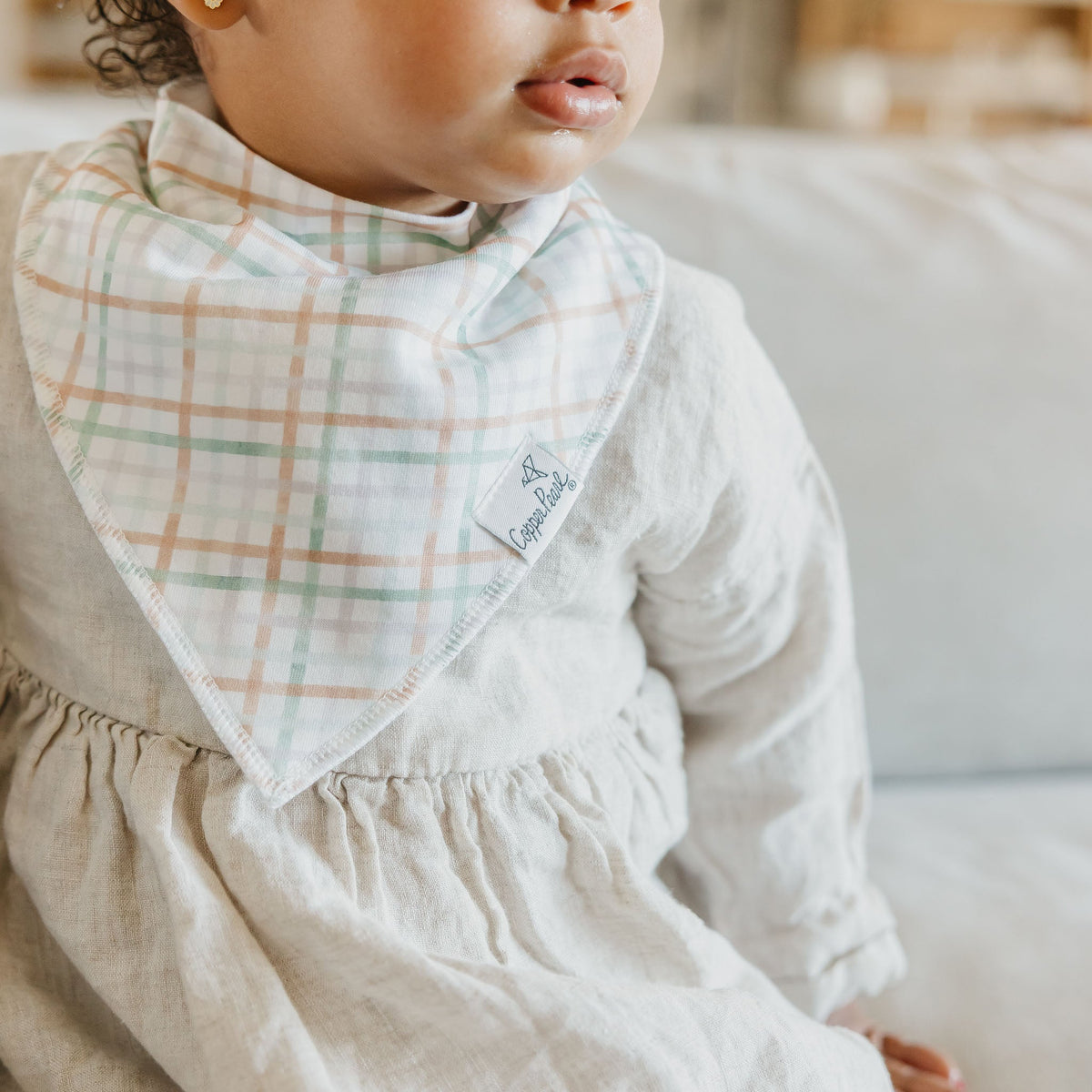 Child wearing a plaid bib with a blurred background