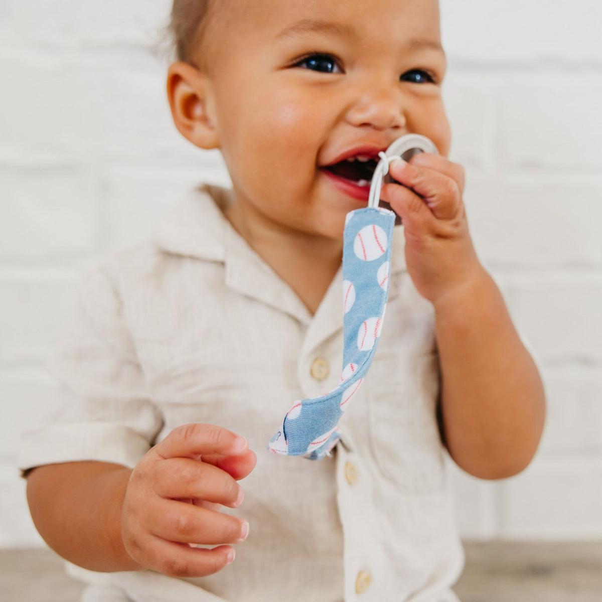 Baby holding a blue teething ring with pink patterns