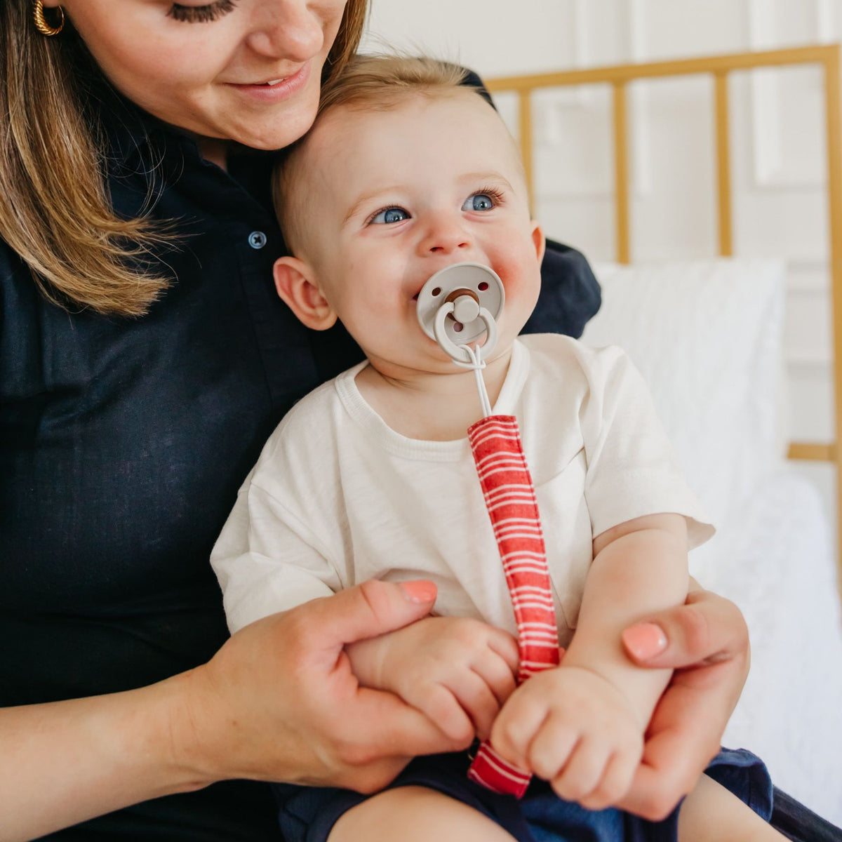 Baby with a pacifier held by a woman in a home setting