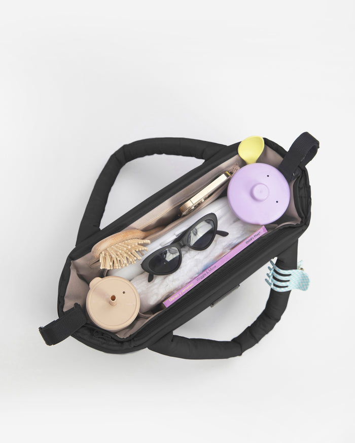 Black toiletry bag with various travel items on a white background