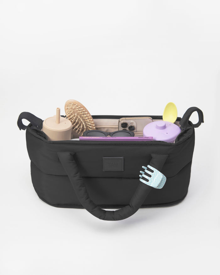 Black organizer bag with various items on a white background