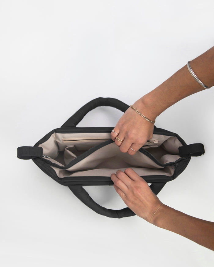 Person opening a black bag on a white background