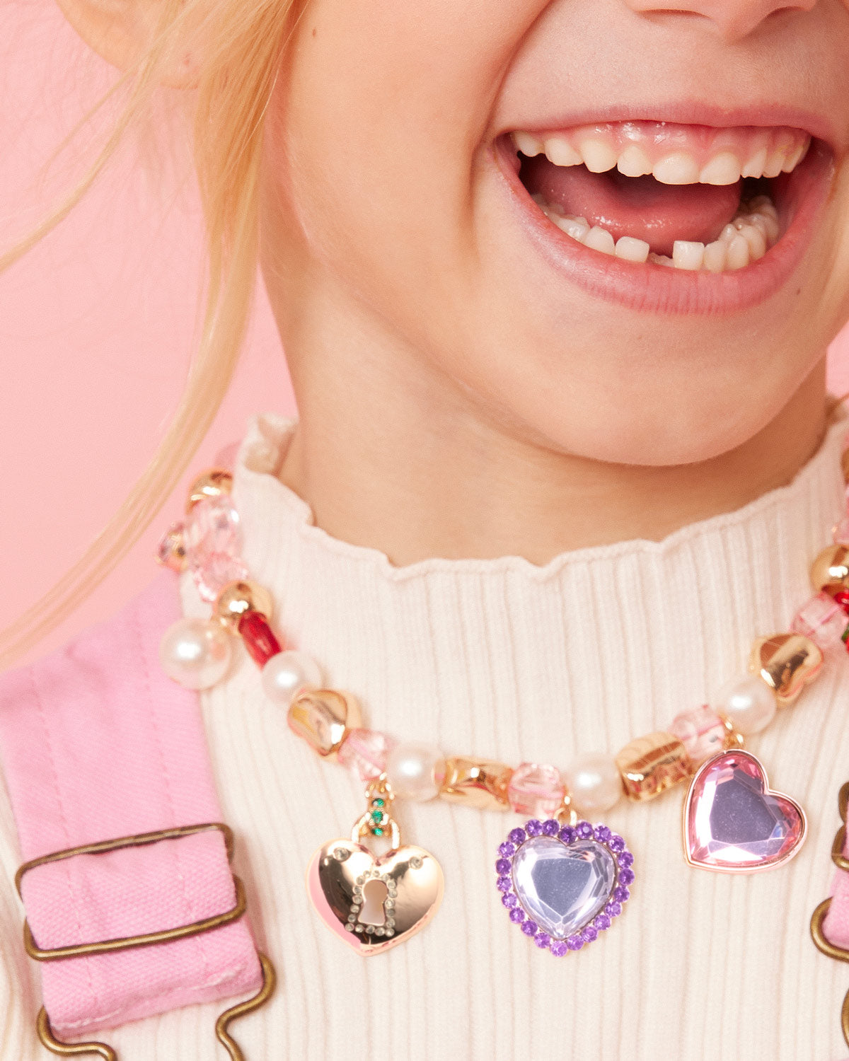 Close-up of a child wearing a colorful necklace with heart-shaped charms.