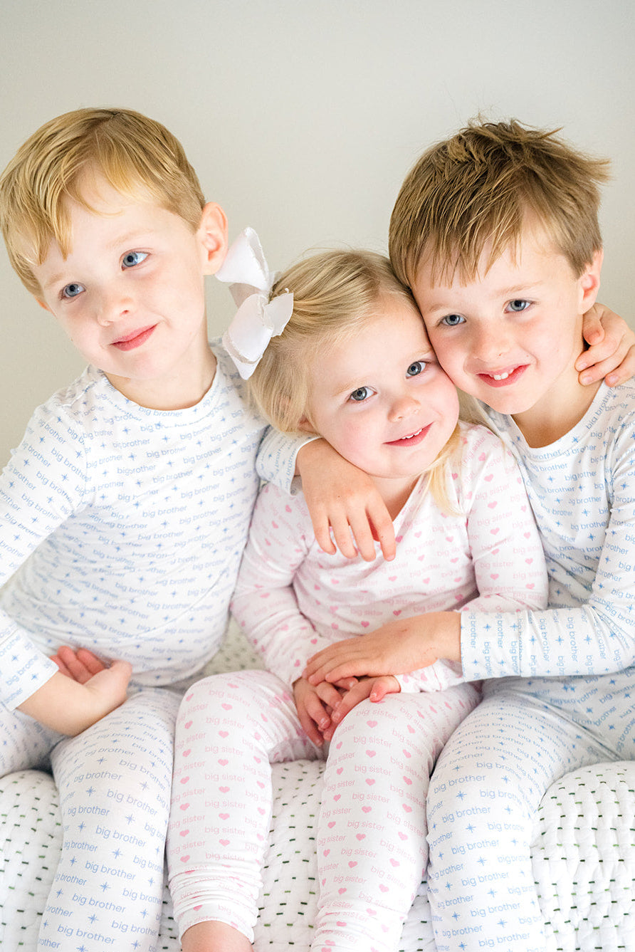 Three children in matching pajamas sitting together on a couch.