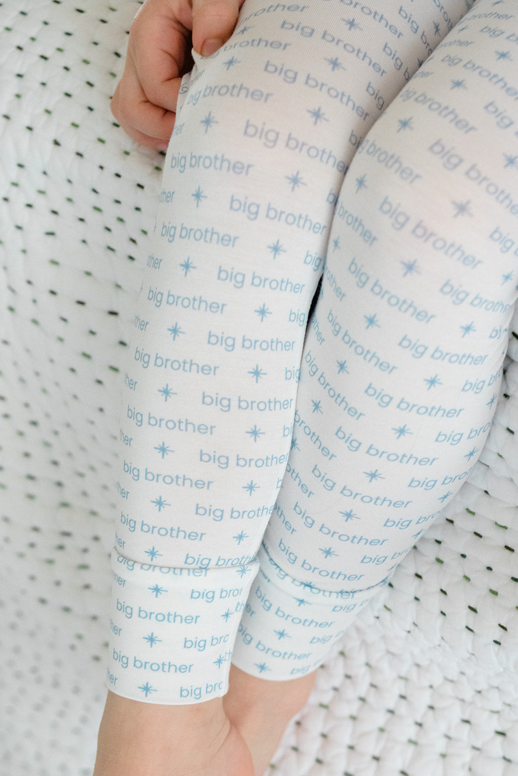 Baby leggings with 'big brother' text on a textured background
