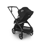 A black stroller and bassinet travel system on a clean white background. The system includes a black stroller with a matching canopy, a black bassinet seat insert, and a black frame with four wheels.