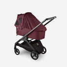 Maroon baby stroller with black frame on a white background