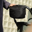 Black stroller organizer attached to a stroller with a blurred background