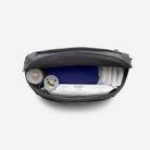 Black diaper bag with baby items including a blue diaper and white wipes on a white background