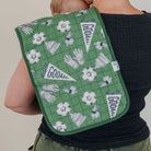 A green padded shoulder pad with a soccer-themed print, worn over the shoulder of a person wearing a black ribbed top.