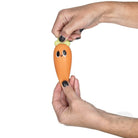 Person holding a small carrot-shaped toy with a face on a white background