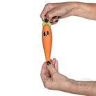 Person holding a carrot-shaped toy with a face on a white background