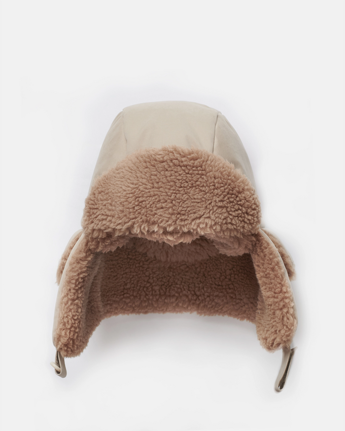Beige winter hat with brown fur trim on a white background