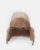 Beige winter hat with brown fur trim on a white background