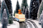 Teddy bear on a toy train in a snowy forest setting