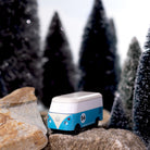 Model of a blue and white van on rocks with a snowy forest background