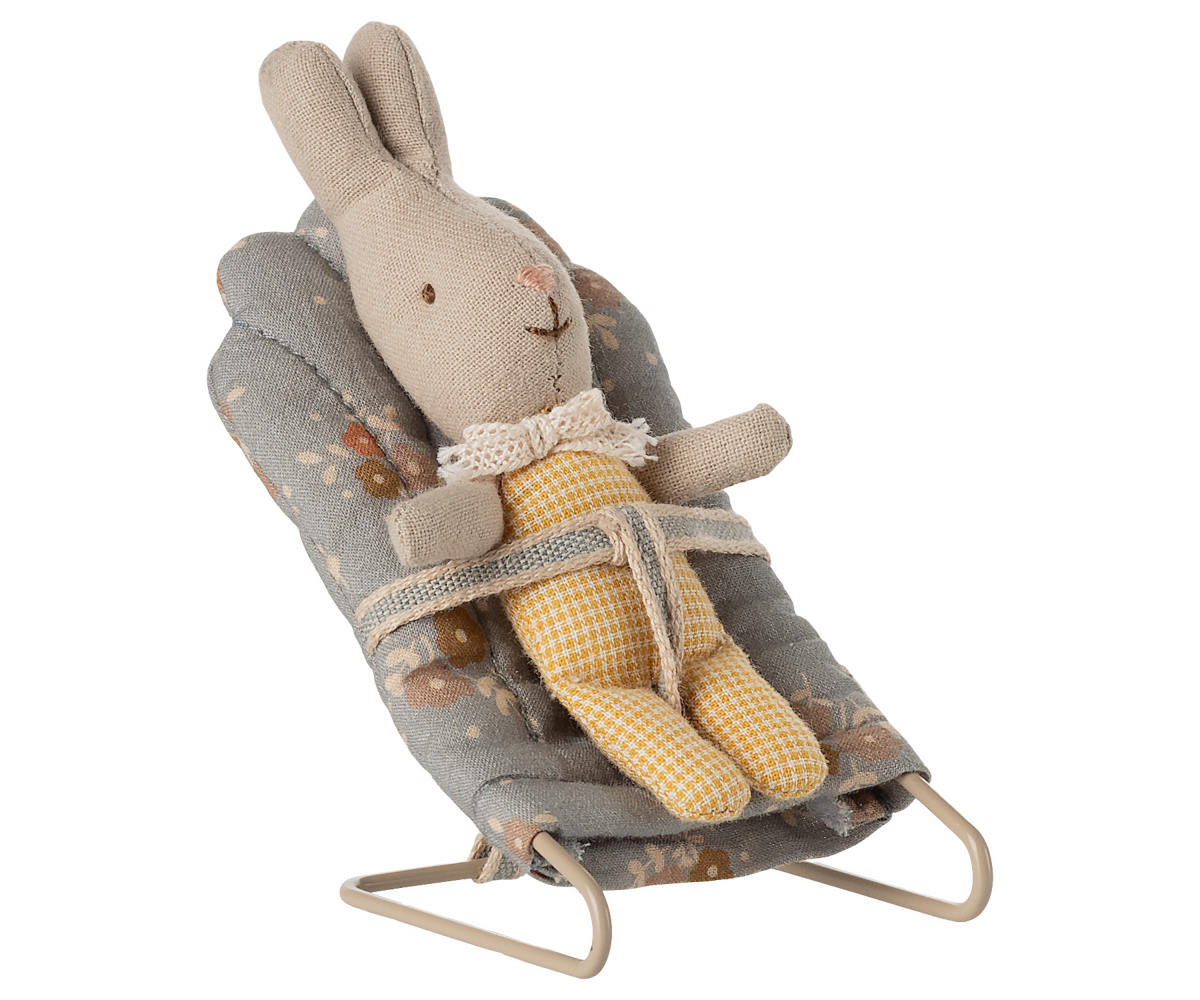 Stuffed rabbit toy in a baby bouncer on a white background