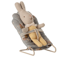 Stuffed rabbit toy in a baby bouncer on a white background