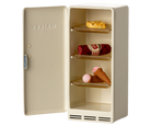 Small beige refrigerator with ice cream cones and a bottle inside on a white background
