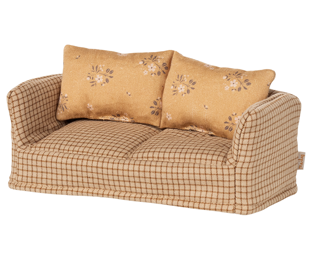 Beige checkered sofa with floral-patterned cushions on a white background