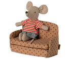 Stuffed mouse toy in a striped shirt sitting on a polka dot couch with a white background