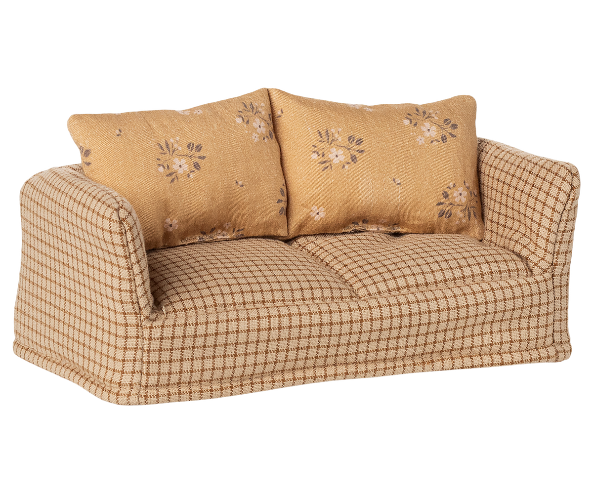 Beige checkered sofa with floral-patterned cushions on a white background