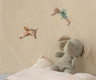Children's room with stuffed animals on a bed against a patterned wall.