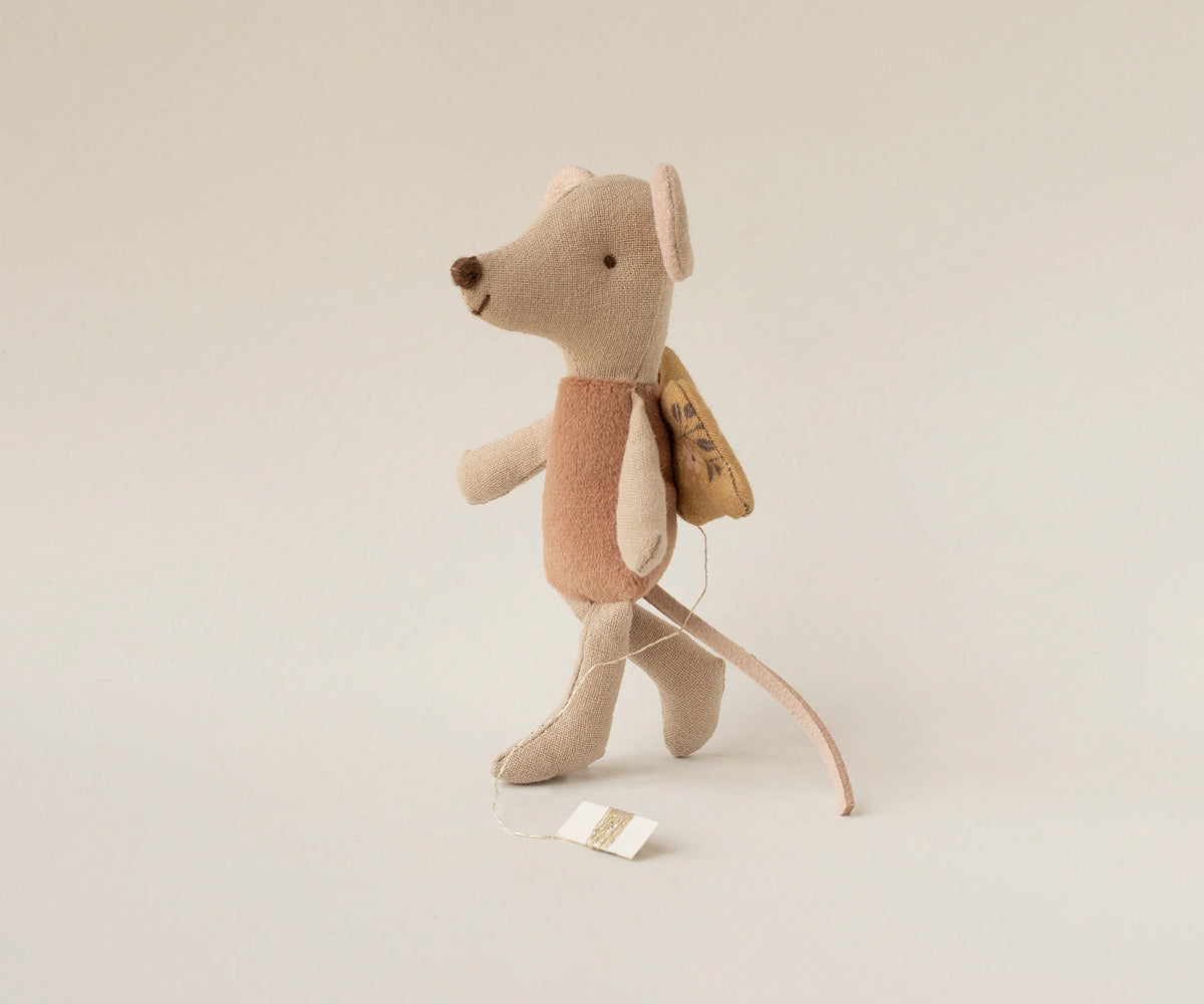 Stuffed mouse toy with a backpack on a light beige background