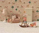 Children's room with toys, chair, and lamp against a wallpapered wall with animal patterns.