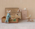 Maileg Mum mouse standing next to a vintage cigar box where Dad mouse sits inside, set against a miniature room scene with a small wardrobe, table, and teapot.