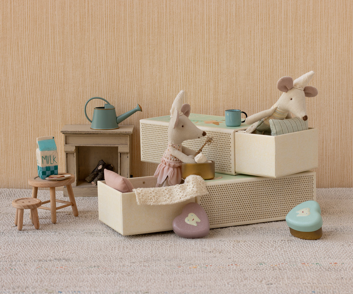 Miniature dollhouse scene with toy animals and furniture on a neutral background
