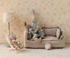 Children's room with plush toys on a sofa and chair against a floral wallpaper background