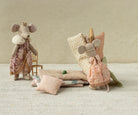 A Maileg toy set showing a Big Sister mouse standing next to a stack of patterned mattresses, a miniature pillow, and a tiny green pea resting on the bed setup.