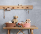 Children's room with wooden shelf, table, and toys against a gray wall.